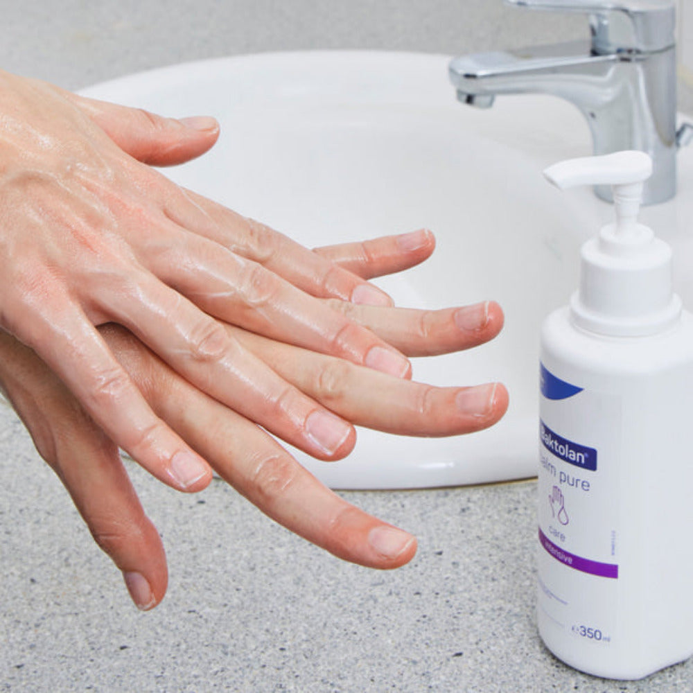 Bild eines Balsams in einem klaren, runden Glastiegel mit einem glänzenden schwarzen Deckel. Der Balsam hat eine cremige, hellgelbe Farbe und ist leicht glanzend. Der Tiegel steht auf einer neutralen, hellen Oberfläche, die das Produkt hervorhebt. In der Nähe des Tiegels sind einige natürliche Zutaten wie Blüten und Blätter verstreut, die ein Gefühl von Natürlichkeit und Pflege vermitteln. Auf dem Deckel ist eine schlichte Beschriftung oder Logo zu sehen, das die Marke und das Produktdesign ergänzt.