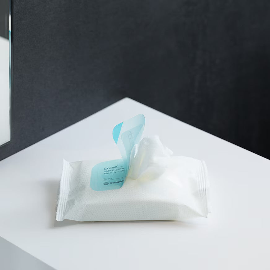 Eine Verpackung der Brava Hautreinigungstücher von Coloplast. Sie ist geöffnet und zeigt ein weißes Hautreinigungstuch.