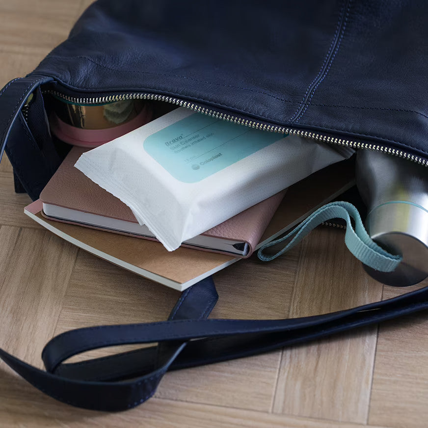 Eine Verpackung der Brava Hautreinigungstücher von Coloplast. Sie ist in einer Damenhandtasche zu sehen.