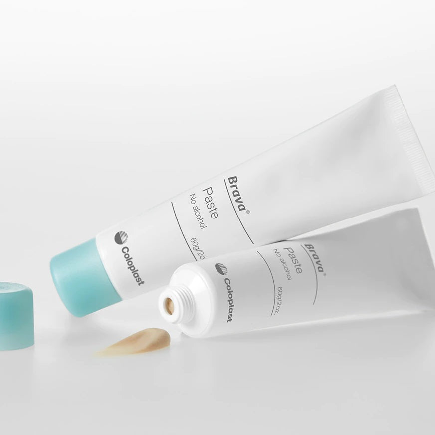 Weißer Behälter mit blauer Kappe und einem gelben Etikett, das den Produkttitel "Brava Paste" in blauer Schrift zeigt. Unter dem Titel steht "alkoholfrei" in kleinerer Schrift, gefolgt von "Stoma Hautschutz". Der Behälter zeigt eine klare Produktbeschreibung und Anwendungshinweise auf der Rückseite. Der Hintergrund ist neutral und hell, was den Fokus auf den Behälter lenkt. Der Gesamtlook vermittelt Sauberkeit und Professionalität, ideal für medizinische Produkte zur Hautpflege für Stoma-Träger.
