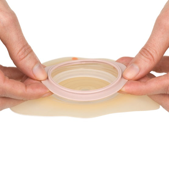 Das Bild zeigt eine DanSac Nova 2 Basisplatte mit einer konvexen Form. Die Platte hat einen Durchmesser von 30 mm und einer Stärkenangabe von 10 mm. Die Oberfläche der Basisplatte ist glatt und in einem neutralen Farbton gehalten, ideal für die Hautverträglichkeit. An der Platte sind außerdem Klebeflächen zu erkennen, die eine sichere Anbringung ermöglichen. Diese Basisplatte ist speziell für die Anwendung bei Stomata konzipiert und bietet ein hohes Maß an Komfort und funktionaler Anpassung.