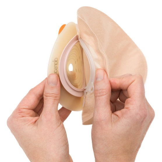 Ein Produktbild zeigt die Dansac Nova 2 Basisplatte mit einer ovalen Form. Die Basisplatte ist in einem neutralen Hautfarbton gehalten und ihre Oberfläche wirkt glatt und leicht glänzend. In der Mitte der Platte gibt es einen runden Ausschnitt, der für die Verarbeitung bei Stoma-Patienten konzipiert ist. Um den Ausschnitt sind Bemaßungen zu sehen, die die Maße von 55 mm, 40 mm und 47 mm angeben. Der Hintergrund ist hell und sorgt dafür, dass die Produktdetails klar und gut sichtbar sind.