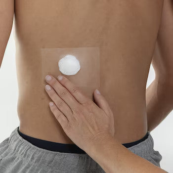 Eine transparente Rolle Fixomull mit einer Breite von 10 cm und einer Länge von 2 m. Die Verpackung zeigt eine klare, durchsichtige Folie, die gleichmäßig aufgerollt ist. Im Hintergrund ist ein unscharfer, heller Untergrund sichtbar, der dem Produkt Kontrast verleiht. Die Seiten der Rolle sind deutlich zu erkennen, während der obere Teil der Folie leicht glänzt. Das Bild offenbart die Flexibilität und die einfache Handhabung des Produkts, das ideal für medizinische Anwendungen und Verbände geeignet ist.