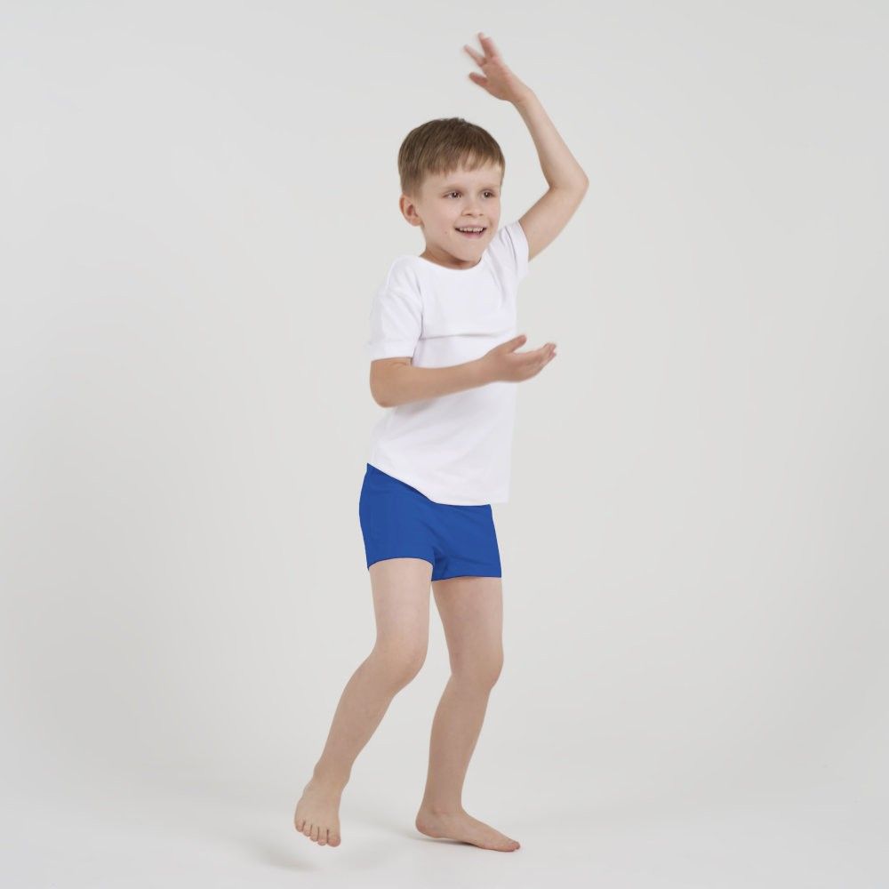 Kind in Bewegung trägt weiße ActivePants mit blauer Hose, tänzelnde Pose vor hellem Hintergrund.