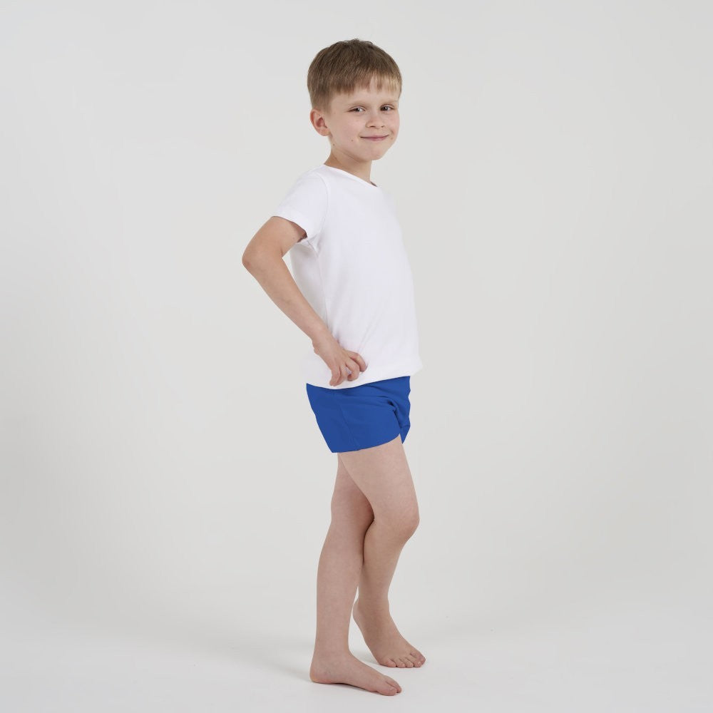 Kind in weißem Shirt und blauen kiwisto ActivePants posiert seitlich mit Händen in der Taille.