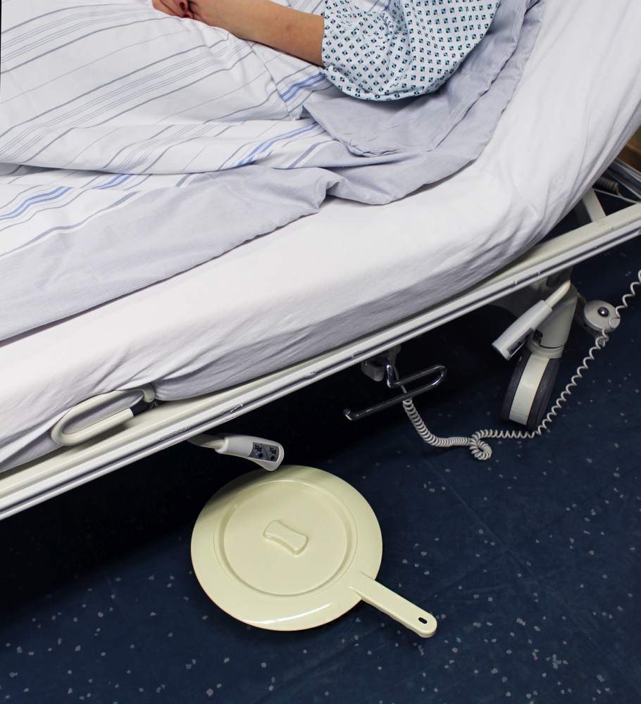 Wiederverwendbare Bettpfanne aus Kunststoff mit Deckel, rund. Die Pfanne hat eine glatte, weiße Oberfläche und einen stabilen, ergonomischen Griff zur einfachen Handhabung. Der abnehmbare Deckel sorgt für Hygiene und Geruchsschutz. Die Pfanne ist in einer hellen Umgebung platziert, um ihre Form und Funktionalität zu betonen. Ideal für die Nutzung im Pflegebereich und bietet Patientenkomfort.