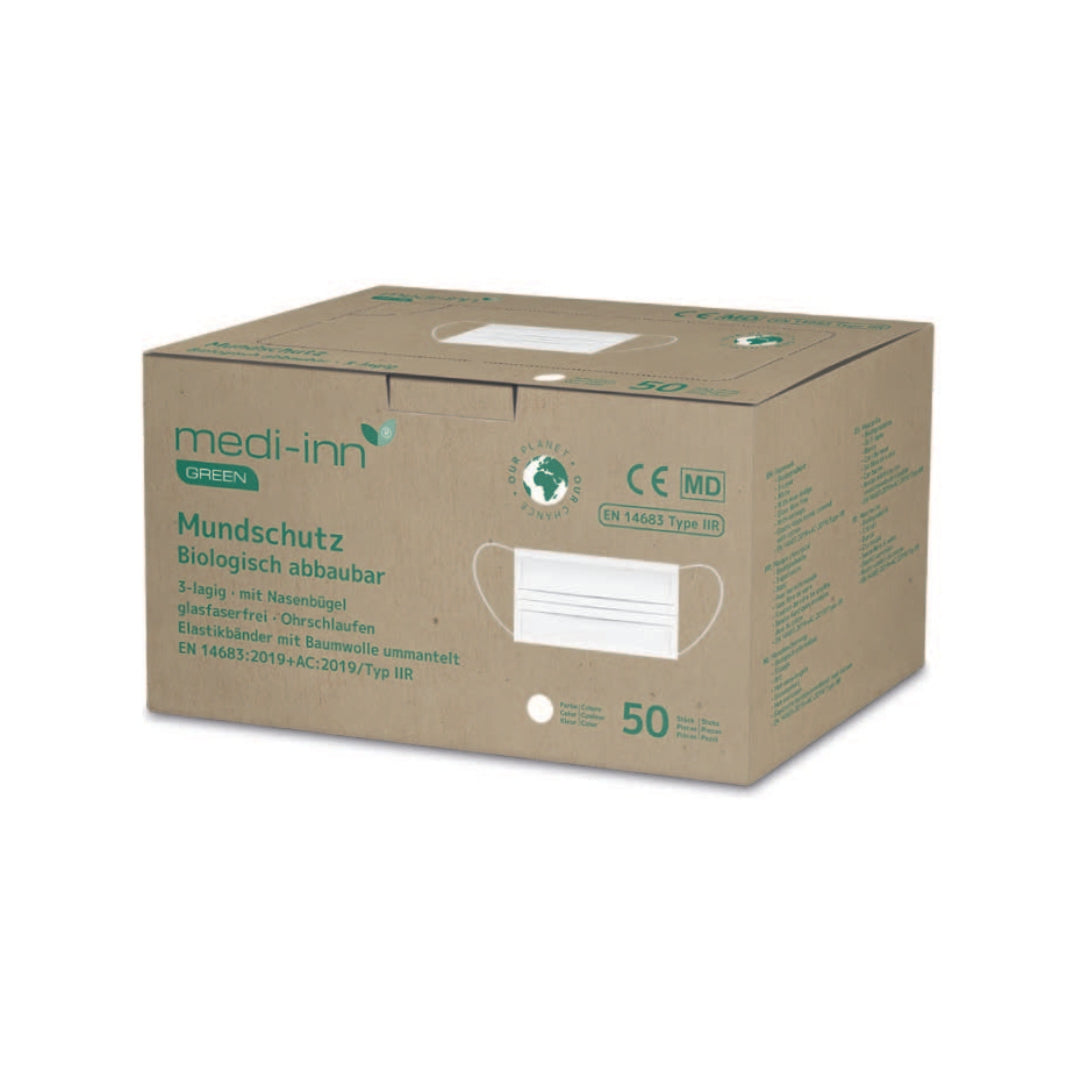 Ein weißer, dreilagiger Mundschutz Typ IIR ist auf einem neutralen Hintergrund abgebildet. Der Maskenstoff ist sichtbar weich und leicht, wobei die drei Lagen deutlich erkennbar sind. Der Mundschutz ist mit elastischen Ohrschlaufen ausgestattet, die farblich auf das Weiß der Maske abgestimmt sind. Auf der rechten Seite befindet sich die Kennzeichnung "biologisch abbaubar", die auf die umweltfreundliche Eigenschaft des Produkts hinweist.