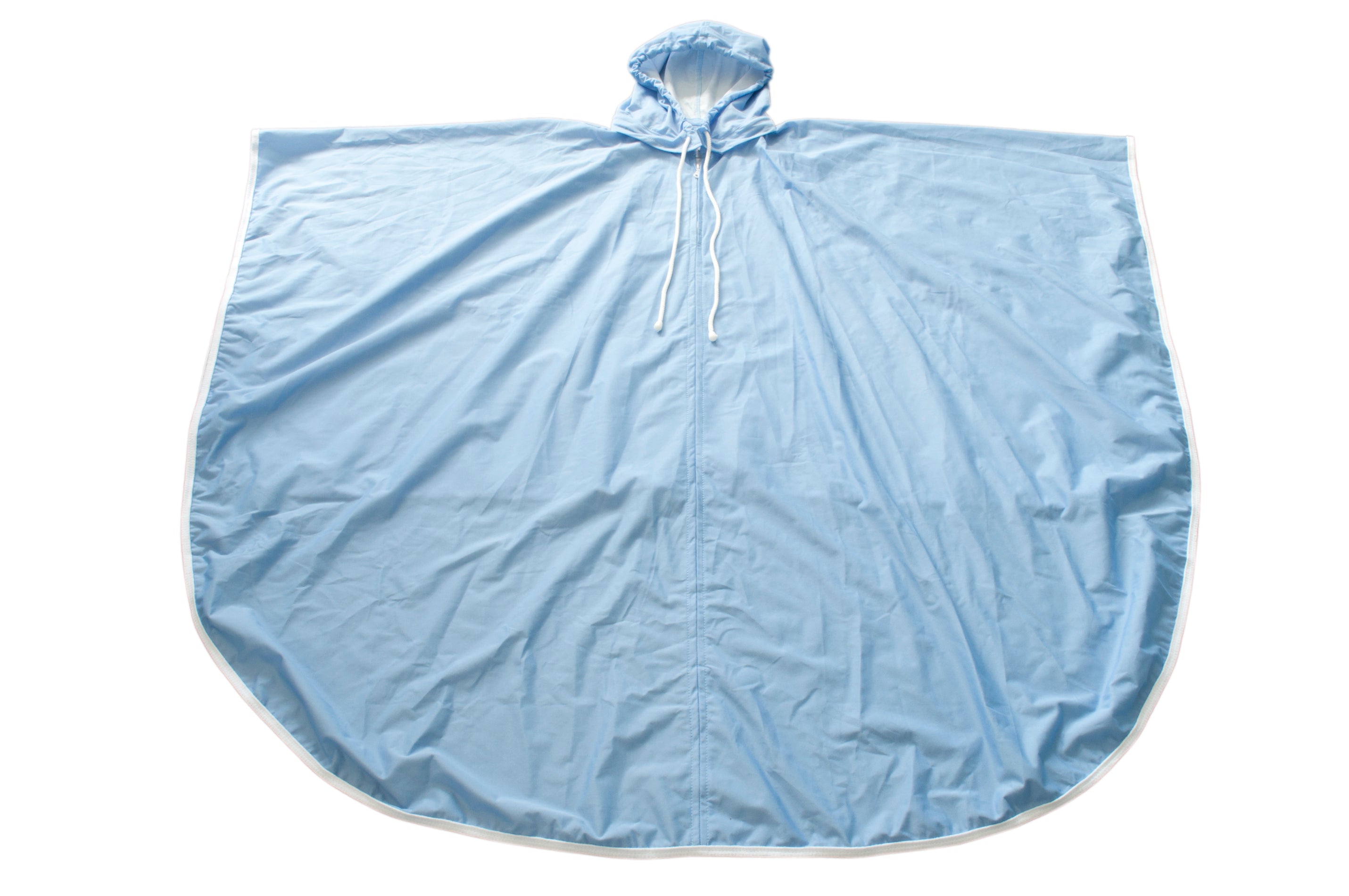 Regenschutz für Rollstühle und Fahrräder, auch als Regenponcho verwendet. Das Produkt in kräftigem Blau ist aus wasserabweisendem Material gefertigt und hat eine großzügige Kapuze, die zusätzlichen Schutz bietet. Der Poncho ist großzügig geschnitten und hat eine praktische Frontöffnung, die das Anlegen erleichtert. Im Hintergrund ist eine smaragdfarbene Wiese zu sehen, die die Funktionalität des Regenmantels unterstreicht.