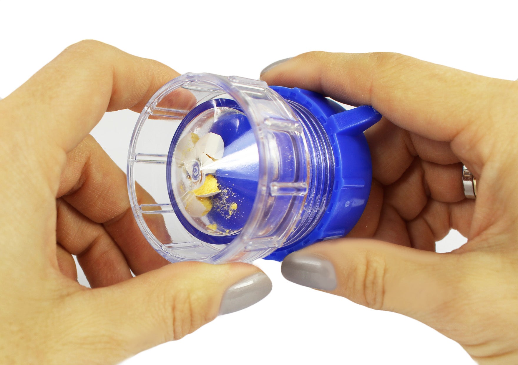 Eine blaue Tablettenmühle mit integriertem Medikamentenfach steht auf einem weißen Hintergrund. Das Produkt besteht aus einem runden, transparenten Behälter mit einem blauen Deckel, der eine leicht strukturierte Oberfläche hat. Der Mörser hat eine runde Form und eine Erhöhung im Inneren, um das Zerkleinern der Tabletten zu erleichtern. Auf der Vorderseite sind drei kleine, herausnehmbare Fächer für Medikamente sichtbar.