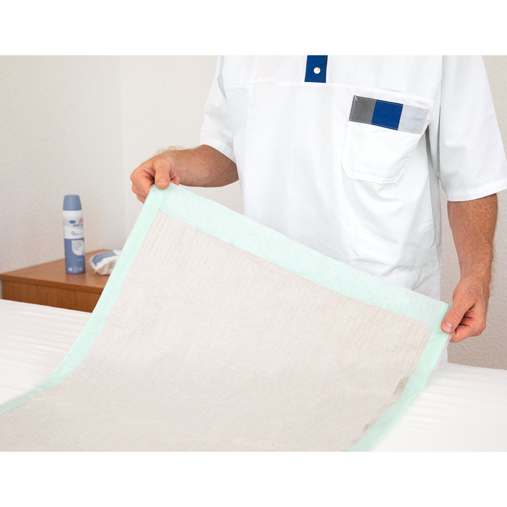 Produktbild zeigt eine Verpackung der Molicare Bettschutzeinlagen in der Größe 60 x 90 cm. Die Verpackung ist weiß mit grünen und blauen Designelementen und trägt die Aufschrift "Molicare Bed Mat Eco" sowie "5 Tropfen" zur Kennzeichnung der Saugstärke. In der unteren Bildhälfte ist die Anzahl von 100 Stück sichtbar. Die Einlagen sind für optimalen Schutz und Komfort konzipiert und richten sich an Menschen mit erhöhtem Pflegebedarf. Der Hintergrund ist neutral, um das Produkt hervorzuheben.