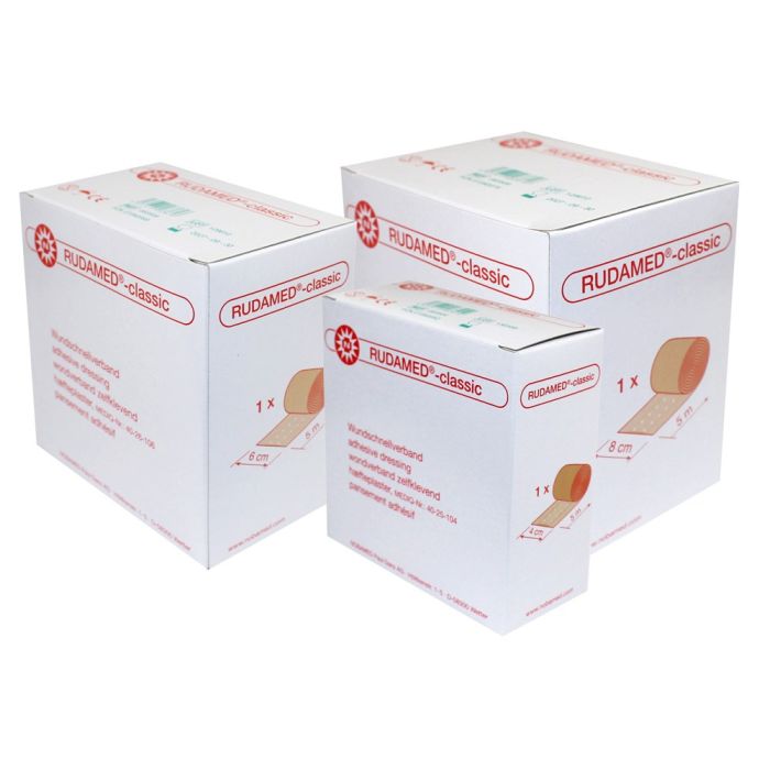 Produktbild eines klassischen Wundpflasters von Noba. Das Wundpflaster wird in einer transparenten Verpackung präsentiert, die eine Rolle mit einem 5 Meter langen Wundschnellverband zeigt. Die Rolle ist mittig positioniert, umgeben von einem weißen Hintergrund, der die Aufmerksamkeit auf das Produkt lenkt. Das Packaging zeigt deutliche Schriftzüge mit dem Markennamen "Noba" und der Produktbeschreibung "Rudamed Classic". Ideal für die Erste Hilfe, um Wunden schnell und effektiv abzudecken.