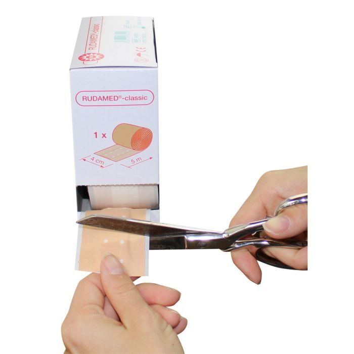 Ein Wundpflaster von Noba Rudolph Classic. Das Produkt ist in einer weißen Verpackung mit blauer Schrift und dem Logo von Noba gestaltet. Auf der Vorderseite sind die Begriffe „Wundschnellverband“ und „5 Meter“ deutlich zu erkennen. Die Verpackung vermittelt einen medizinischen und hygienischen Eindruck. Im Hintergrund ist eine schlichte, einfarbige Oberfläche, die den Fokus auf das Pflaster lenkt. Das Design ist klar und funktional, ideal für den Einsatz in Erste-Hilfe-Situationen.
