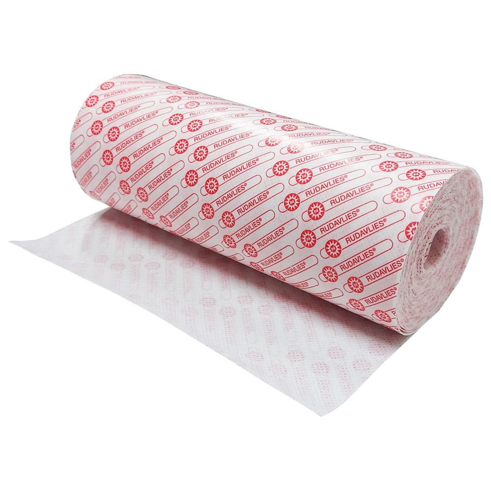 Ein weißes, weich strukturiertes Klebevlies auf einem rechteckigen Hintergrund. Das Vlies ist in einer Rolle aufgewickelt und wirkt leicht und atmungsaktiv. Die obere Kante des Produkts zeigt eine transparente Folie, die die Klebeseite schützt. Auf dem Vlies sind kleine abgerundete Ecken zu erkennen. Im Hintergrund ist unscharf eine Mangel oder eine Arbeitsfläche zu sehen, die einen handwerklichen Eindruck vermittelt.