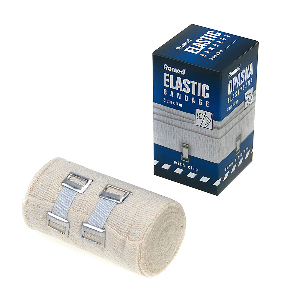 Bild zeigt eine elastische Fixierbinde mit einer Breite von 15 cm und einer Länge von 5 m, verpackt in einer transparenten Folie. Die Binde hat eine beige Farbe und ist in einem klassischen, schlichten Design gehalten. Deutlich erkennbar ist die eingearbeitete Halteklammer, die für zusätzliche Stabilität sorgt. Im Hintergrund sind unscharfe, helle Flächen zu sehen, die den Fokus auf das Produkt lenken.