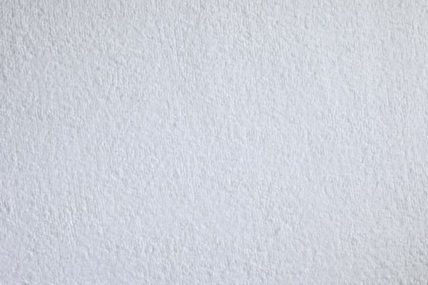 Das Bild zeigt ein weiches, griffiges Spannbetttuch aus Frottee in einem hellen, neutralen Farbton. Es ist auf einer Matratze drapiert, die auf einem Bettrahmen liegt. Die Kanten des Betttuchs sind ordentlich um die Matratze gespannt, sodass eine glatte Oberfläche entsteht. Das Frottee-Material ist sichtbar angenehm und kuschelig, was auf hohen Komfort hinweist. Die Lichtverhältnisse sorgen für eine ansprechende Darstellung der Textur des Stoffes.