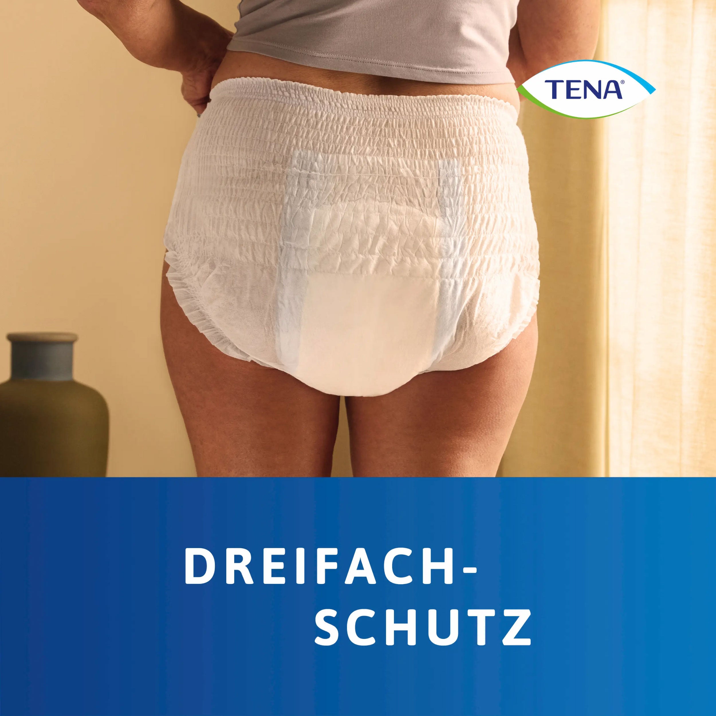 Rückansicht einer angezogenen Tena Pants Plus Medium Inkontinenzhose mit dem Hinweis: Dreifachschutz.