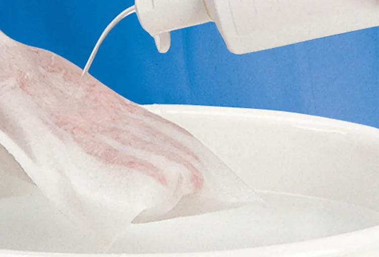 Ein Bild zeigt eine Packung mit Einmal-Waschhandschuhen in der Farbe Blau. Die Handschuhe sind in einer transparenten Kunststoffhülle verpackt, die auf einem weißen Hintergrund liegt. Auf der Verpackung sind die Handschuhgröße, die Anzahl der enthaltenen Handschuhe und Informationen zur Anwendung abgedruckt. Die Handschuhe sind einzeln entnehmbar und sind besonders geeignet für die persönliche Hygiene und Reinigung.